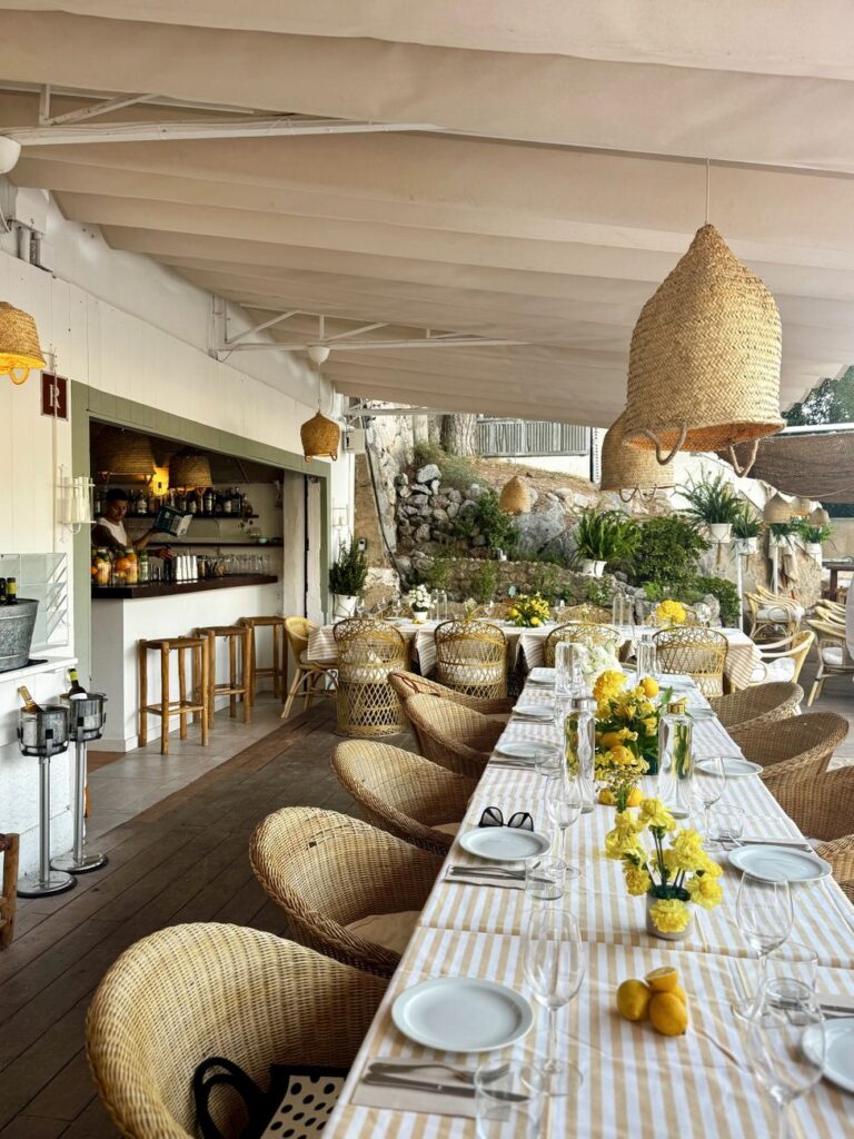 Chic outdoor dining setup with wicker chairs and yellow flowers. Perfect for events.